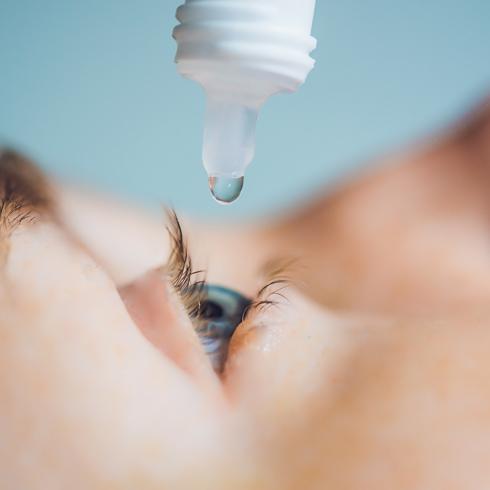 Closeup of eyedropper putting liquid into open eye.