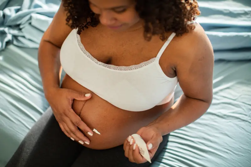 Close up of a Young pregnant Hispanic woman using a spray cream on her belly