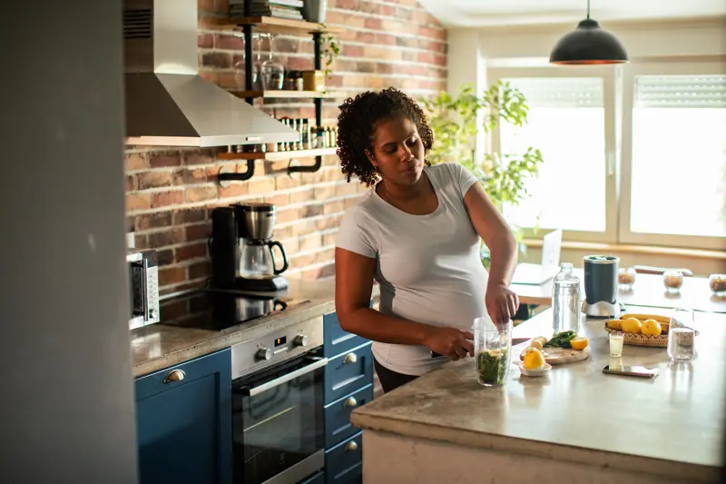 Close up of a Young Pregnant Woman preparing a healthy smoothie in the kitchen