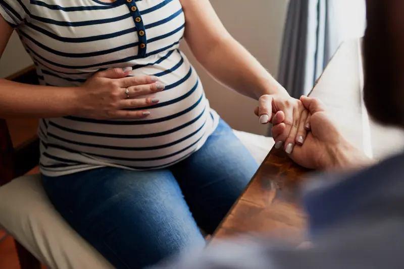 Cropped shot of a pregnant woman holding hands wth her husband at home