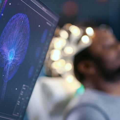 Monitors Show EEG Reading and Graphical Brain Model. In the Background Laboratory Man Wearing Brainwave Scanning Headset Sits in a Chair with Closed Eyes. In the Modern Brain Study Research Laboratory