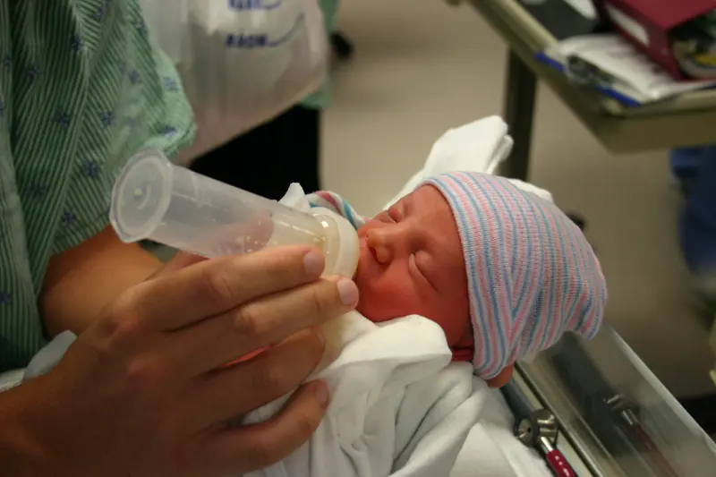 The hands of a new father feeding his newborn preemie son the first drops of mommy's colostrum.