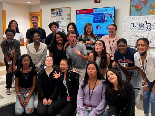 A group of high school students poses in a campus hallway