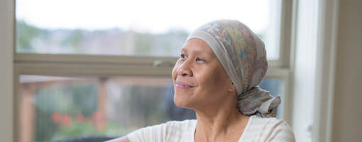 Elderly ethnic female cancer patient looking out a window