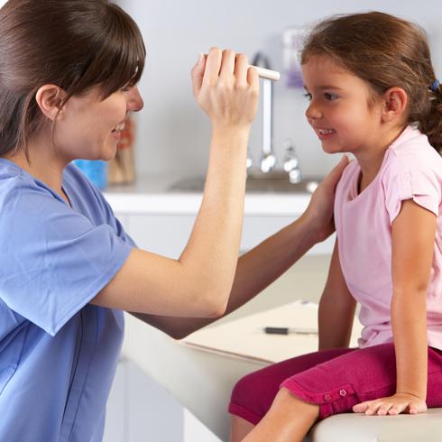 Doctor Examining Child's Eyes In Doctor's Office