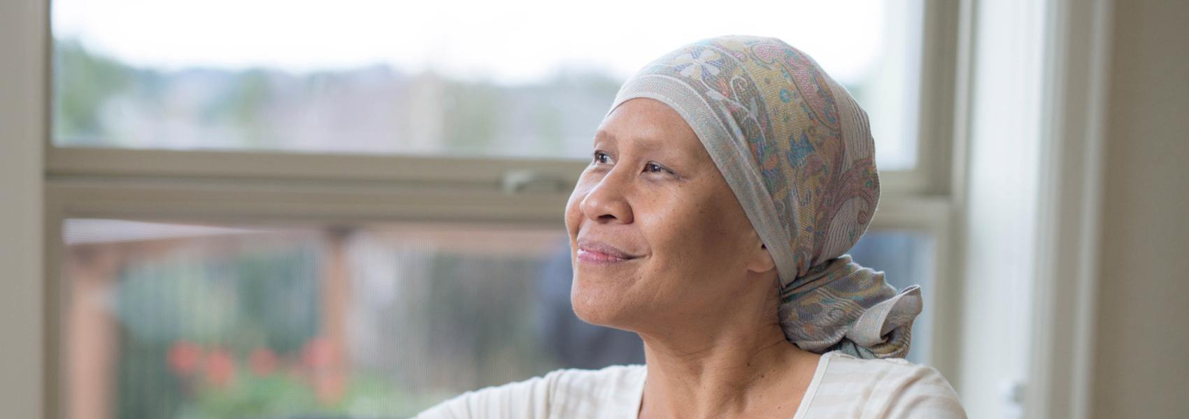 Elderly ethnic female cancer patient looking out a window