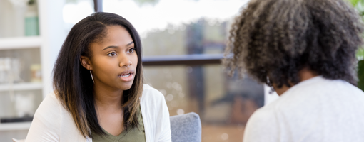 An adolescent Black girl gestures animatedly and looks serious/concerned as she talks to an adult Black woman (who is facing away from the camera)