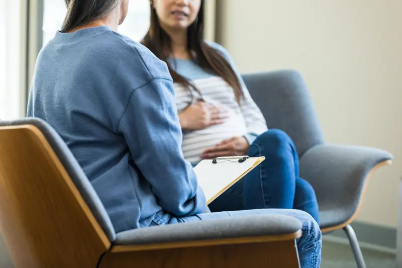 An unrecognizable female counselor and an unrecognizable pregnant woman have a serious conversation.