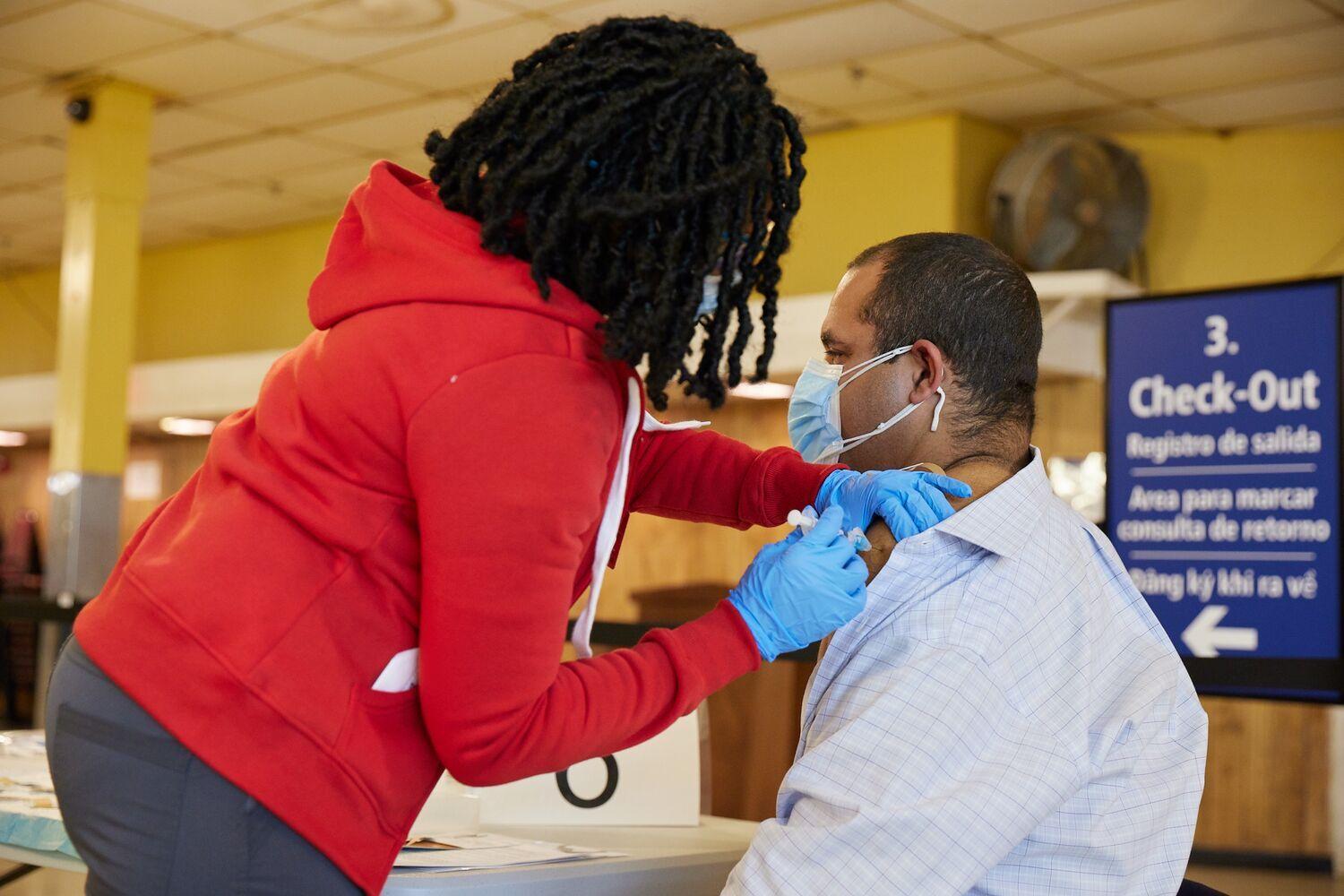 Man waiting in chair for vaccination from nurse